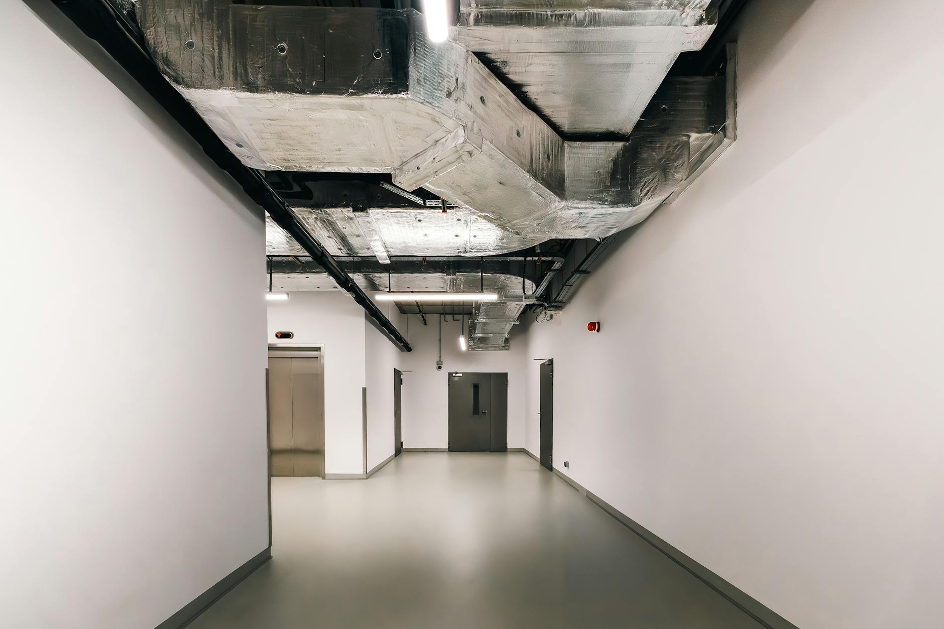 Spacious industrial hallway featuring exposed HVAC ductwork and modern design elements.