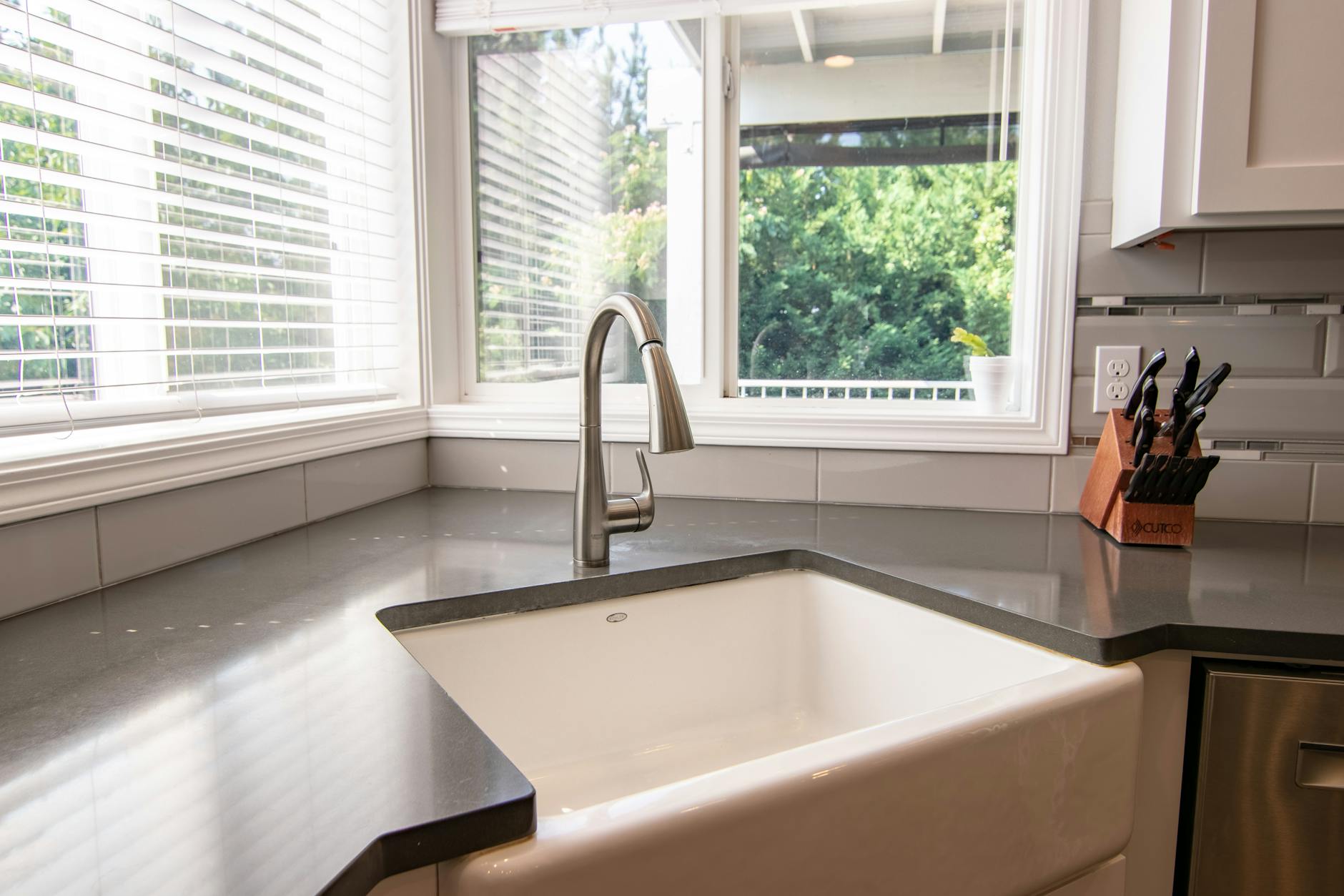 Stylish kitchen sink with stainless steel faucet and knife block by a bright window.
